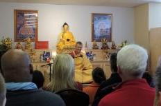 Visitors at the opening of the Akanishta Kadampa Buddhist Center &amp; Bookstore hear teachings from the tradition (Courtesy photo).