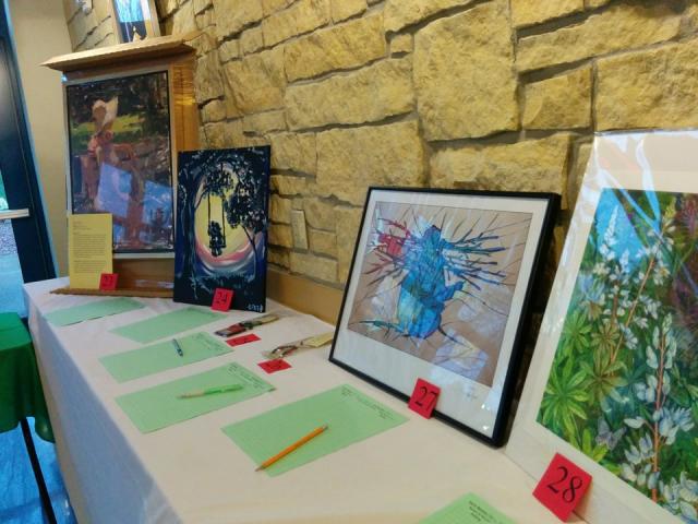 Guests bid on paintings done by Hmong artists, among other items like jewelry, hats and books, at the evening’s silent auction. (Laura Grulke/Madison Commons)