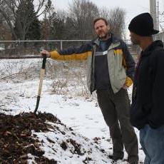 Hansen shows off the compost pile at the Goodman Community Center garden as TEENWorks employee Derrick McDaniel looks on