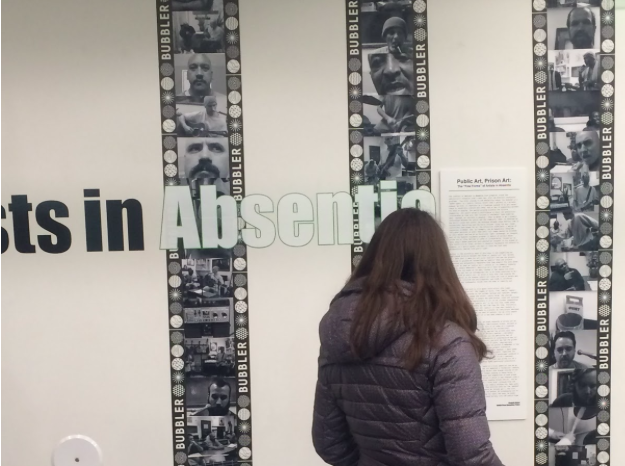 A patron scans an excerpt at the entrance of the exhibition. (Melissa Behling/Madison Commons)