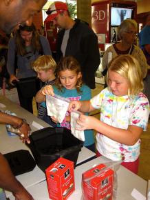 Volunteer, Eric Wise, looks on as two kids pull their freshly made ice cream out of the ice bath