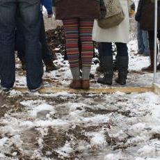 Conference participants stand on the skeleton of a hoop house to stay dry on a tour of the Goodman Community Center gardens.