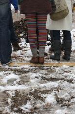 Conference participants stand on the skeleton of a hoop house to stay dry on a tour of the Goodman Community Center gardens.