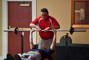 volunteer coach assisting lifting athletes with disabilities.