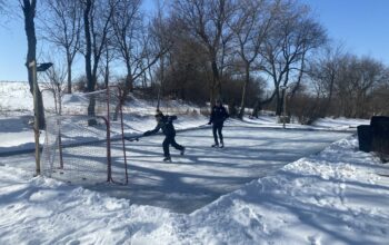 Jake (left) and Hayden (right) taking turns shooting at the net on their backyard ice rink.