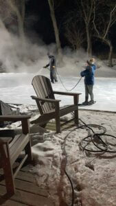 Bryan Ellefson and his son, Jake, spraying water on the ice rink to resurface it.