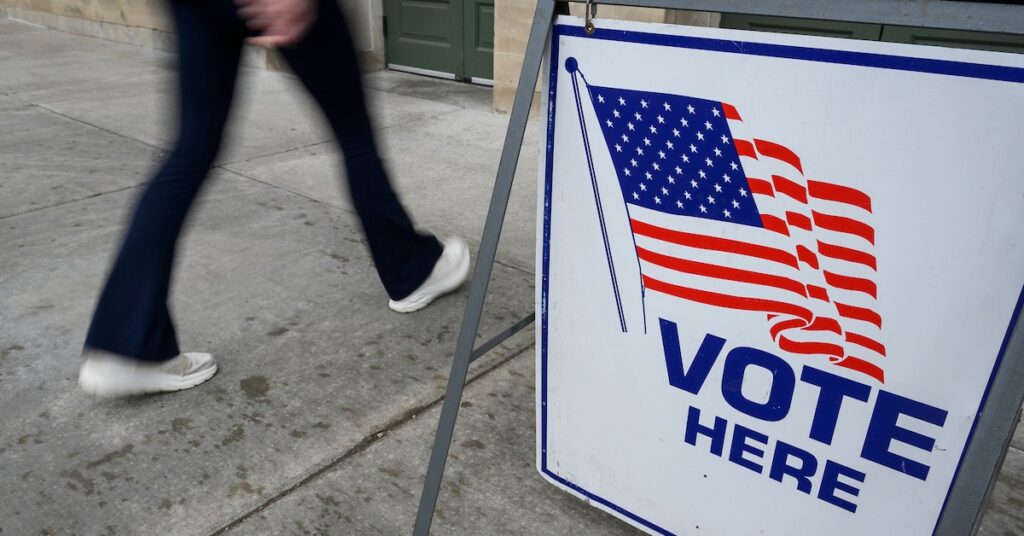 On Election Day, April 4, 2023, pedestrians walk past a “Vote Here” sign at the entrance to the Memorial Union at the University of Wisconsin–Madison, one of several official polling places for UW–Madison students living on campus. (Photo by Althea Dotzour / UW–Madison)