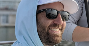 Dave Elsmo smiles, sitting at the UW union and looking out on Lake Mendota. 