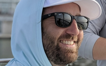 Dave Elsmo smiles, sitting at the UW union and looking out on Lake Mendota.