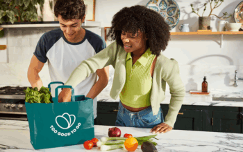 Two shoppers opening a bag of food from Too Good to Go