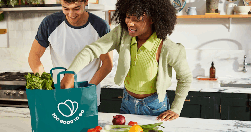 Two shoppers opening a bag of food from Too Good to Go