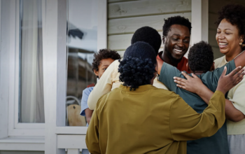 A crowd of people hug each other at the entrance to a home