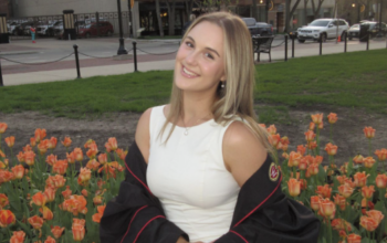 A young blonde woman with a white dress and a graduation gown.