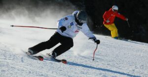 Skiier in a white coat goes down the hill
