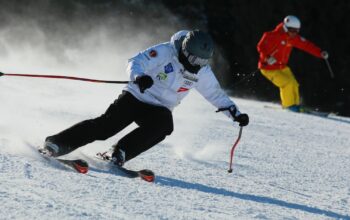 Skiier in a white coat goes down the hill