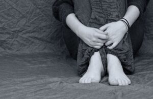 A white person's legs with their arms wrapped around them. You cannot see the head.