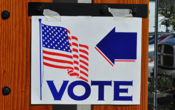 Sign with an American flag and arrow pointing to VOTE